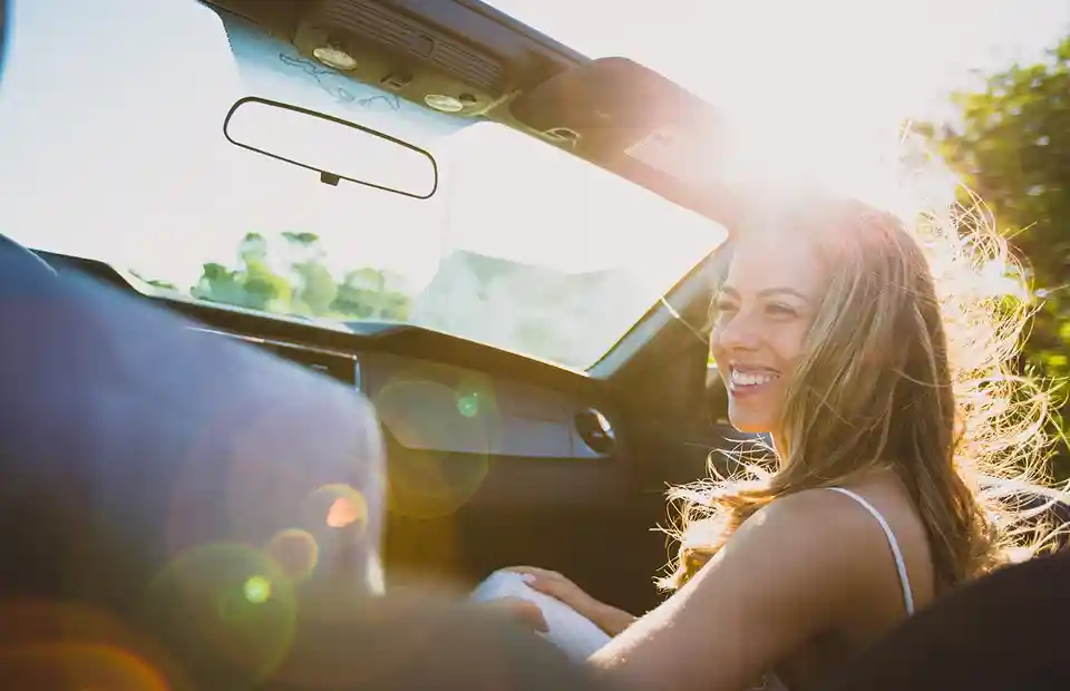 Pareja disfrutando un paseo en auto, se enfoca a la copiloto sonriendo