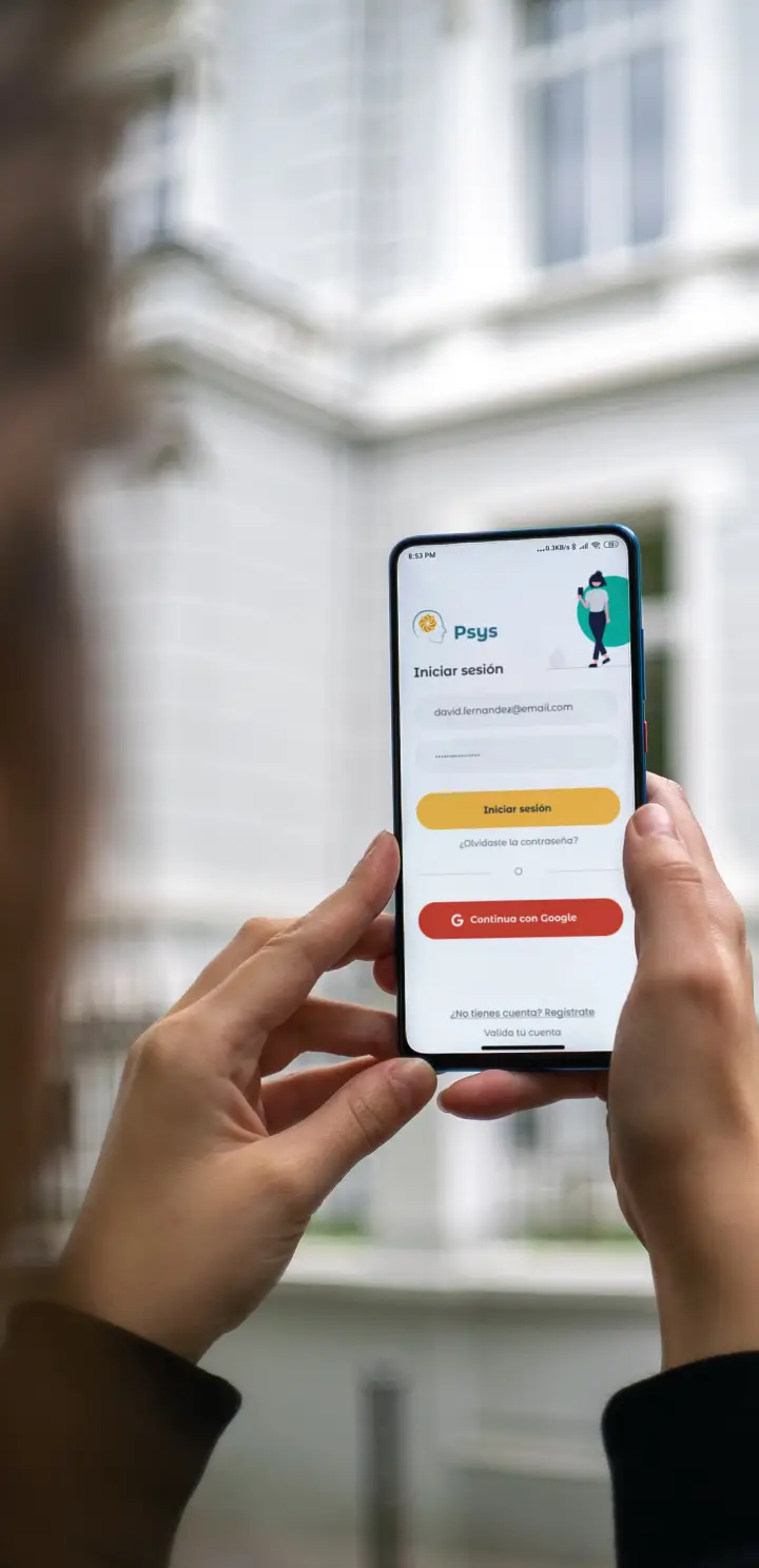 Persona sosteniendo un teléfono móvil al aire libre que muestra la pantalla de inicio de la app Psys